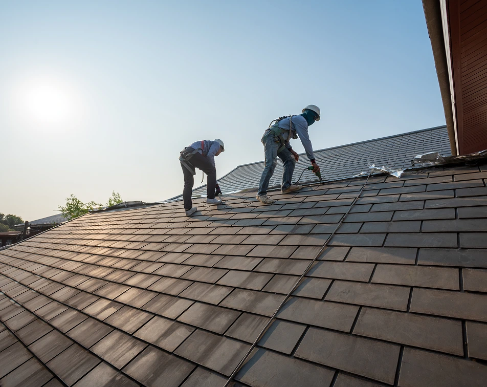 roofer working special protective work wear gloves using air pneumatic nail gun repair replace roofing tiles top new roof construction residential building